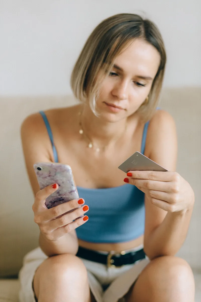 Eine junge Frau nutzt ein Smartphone und eine Kreditkarte.